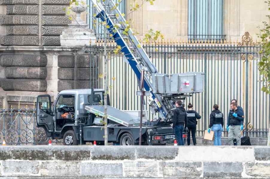 Police detectives gather around an elevator lift truck abandoned at the Louvre after a heist