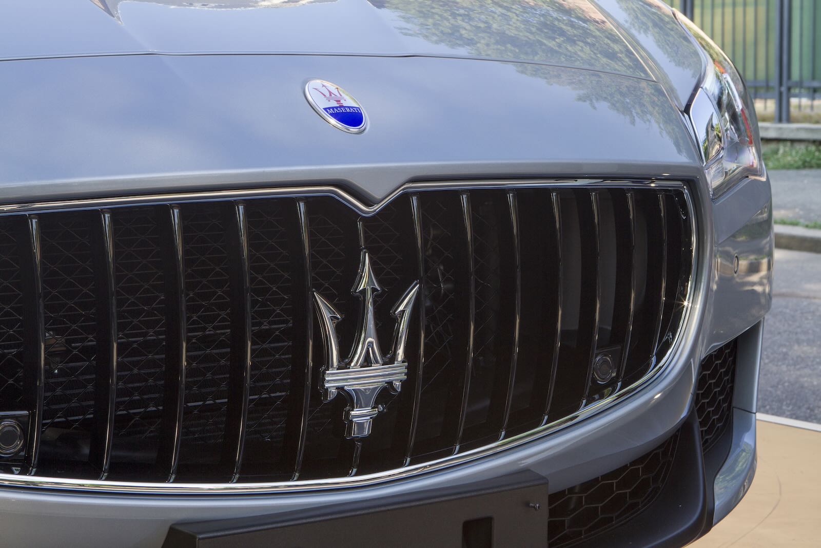The Maserati logo and badge on the grille of a luxury car.