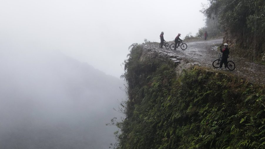 Bicyclists stand on the edge of a cliff on Yungas or Death Road in Bolivia