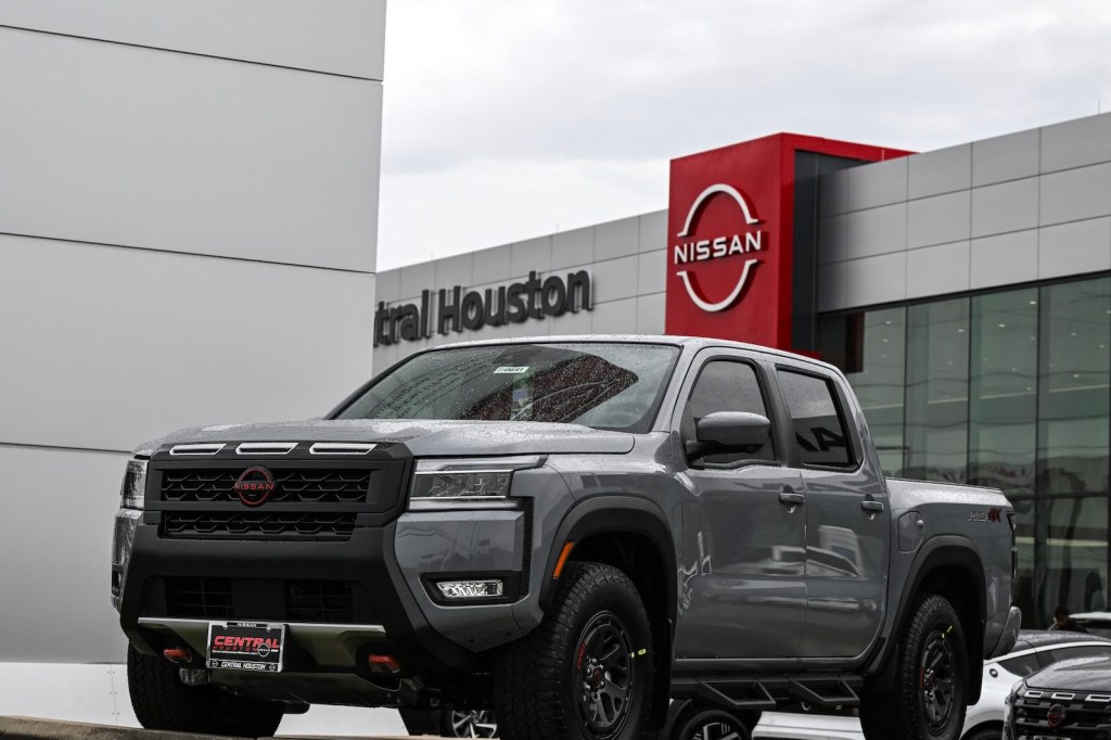 Mid-size Nissan Frontier pickup truck parked in front of a dealership.