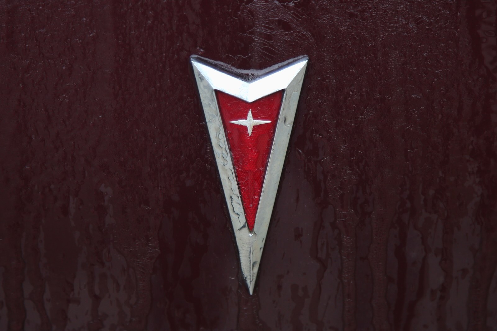 The red arrowhead logo on the hood of a classic Pontiac car.