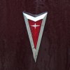 The red arrowhead logo on the hood of a classic Pontiac car.