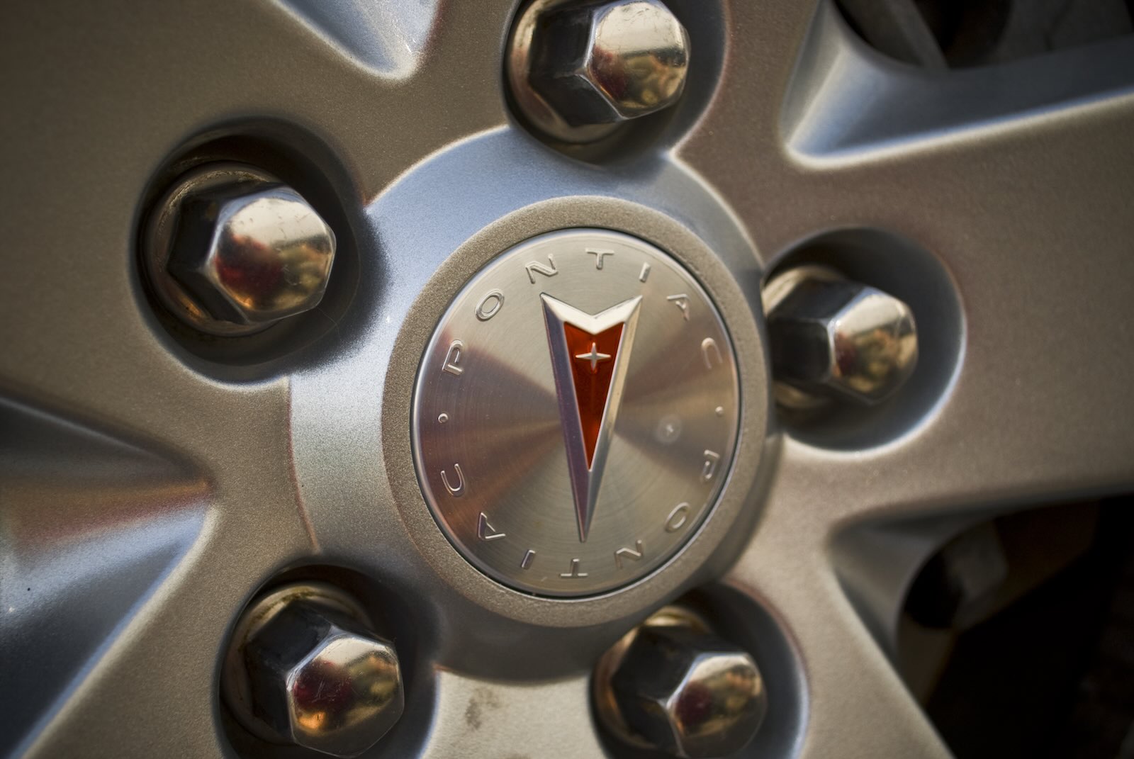 The Pontiac arrowhead badge and brand name on the hub of a car wheel
