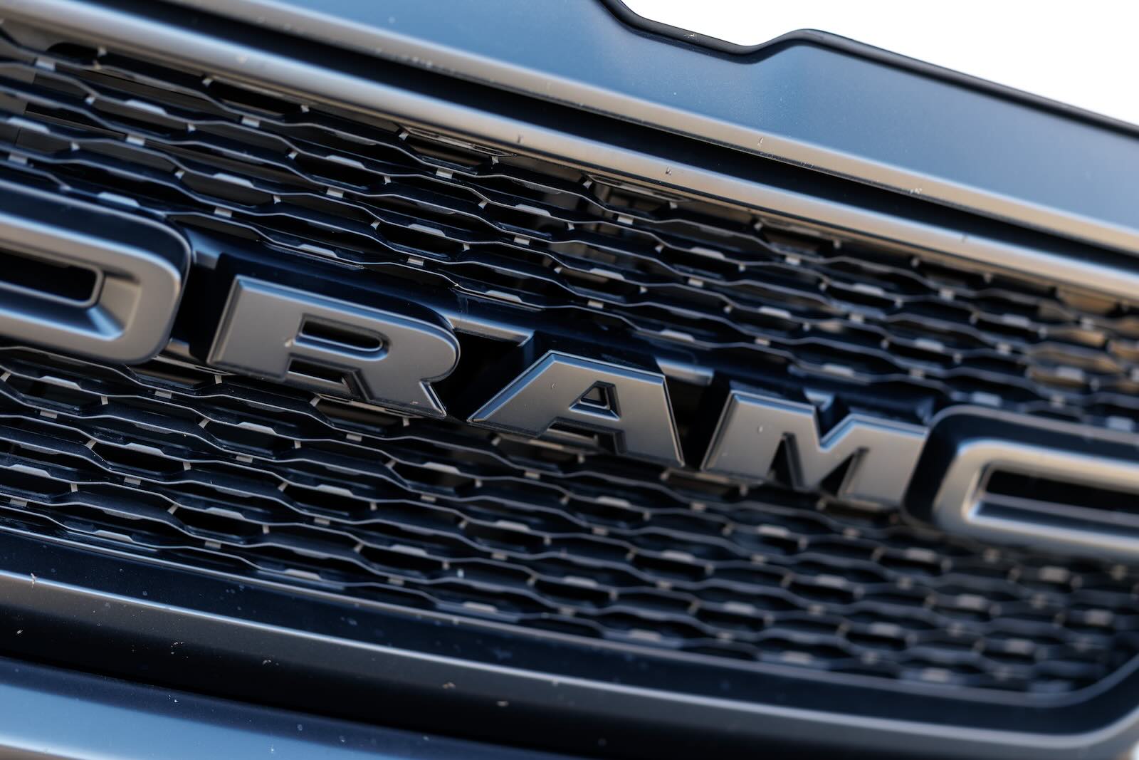 The Ram logo on the black grille of a full-size pickup truck