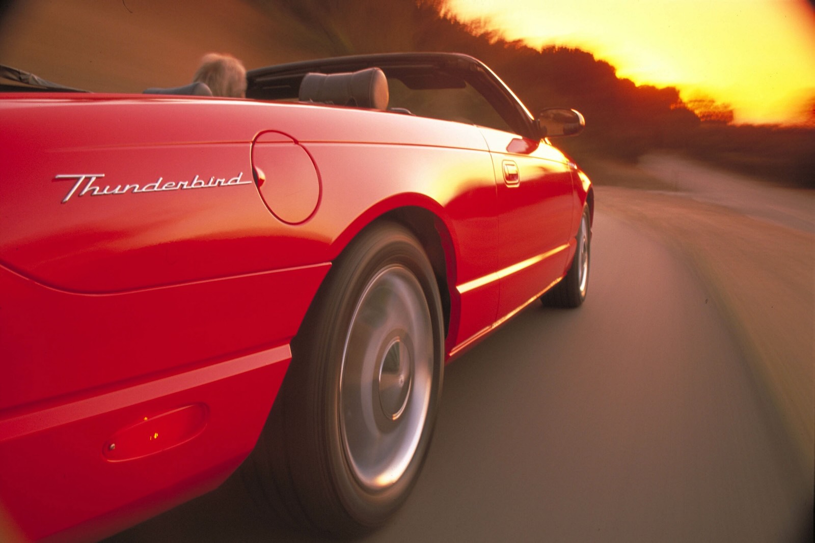 Red Ford Thunderbird convertible, Florida sunset visible in the background.