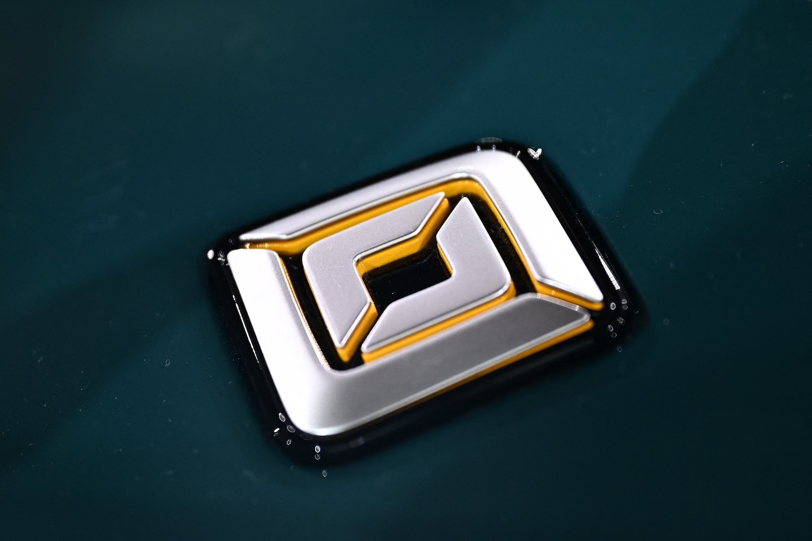 The four-point Rivian logo on the badge of a green EV.