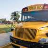 The grille of a yellow school bus, a playground visible in the background.