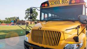 The grille of a yellow school bus, a playground visible in the background.