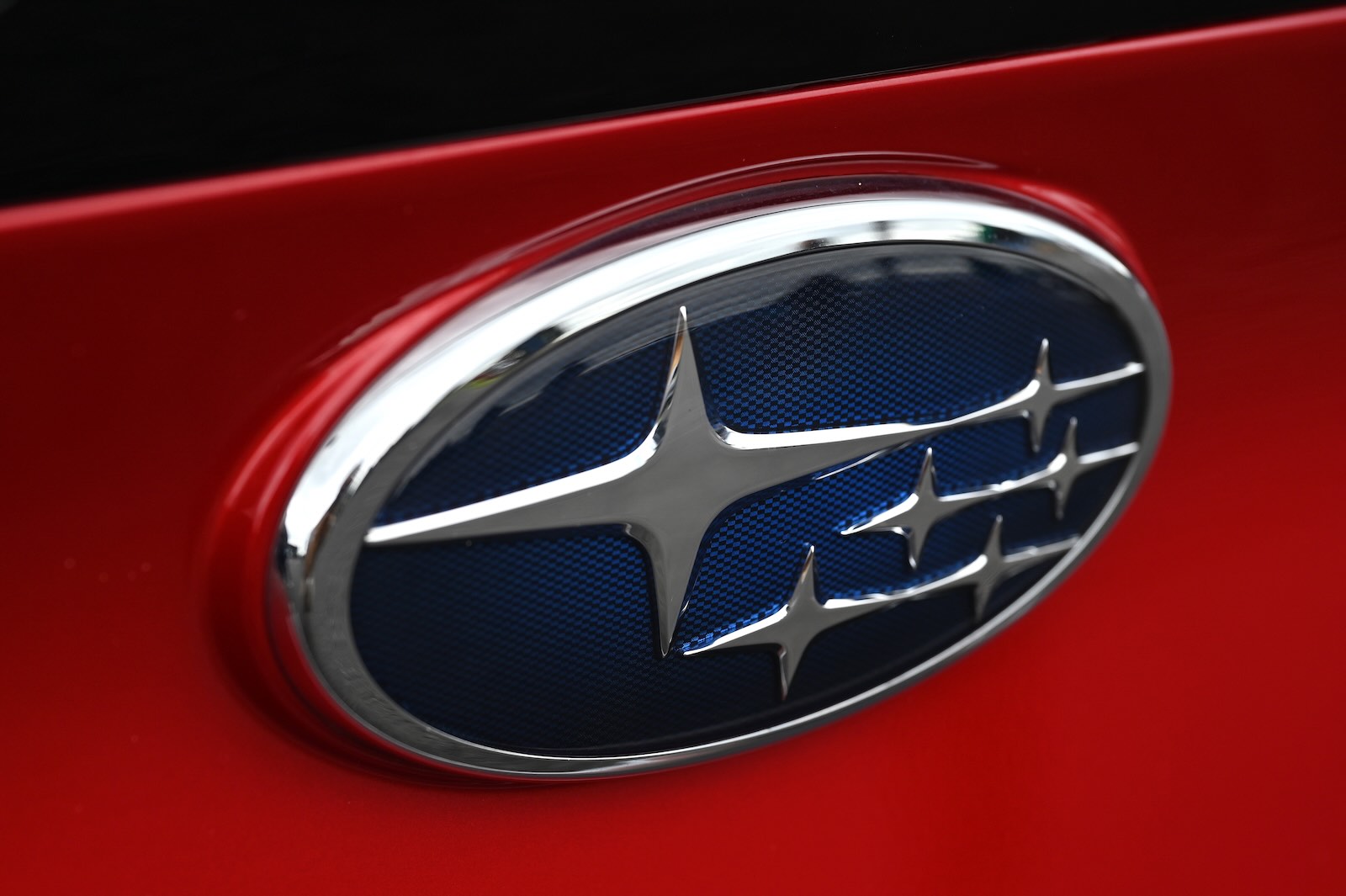 The constellation logo badge on a red Subaru car.