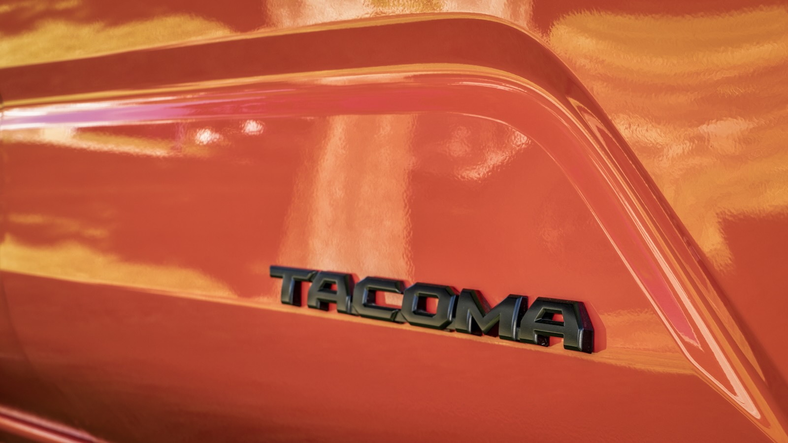Black Tacoma badge on the side of an orange Toyota truck