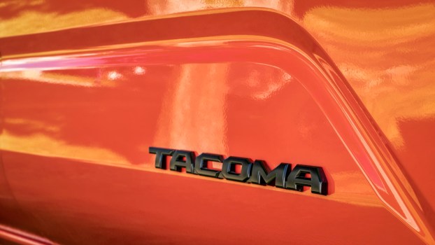 Black Tacoma badge on the side of an orange Toyota truck