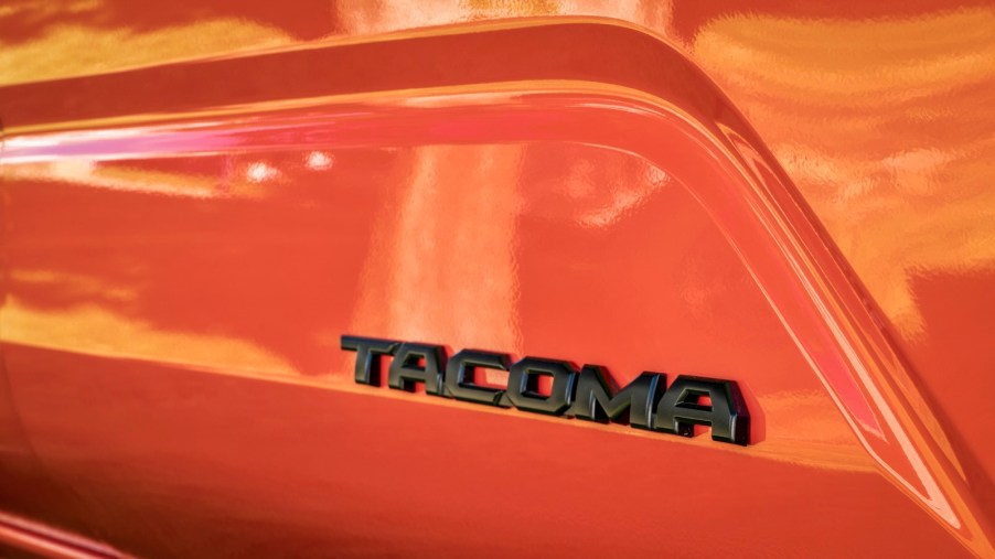 Black Tacoma badge on the side of an orange Toyota truck