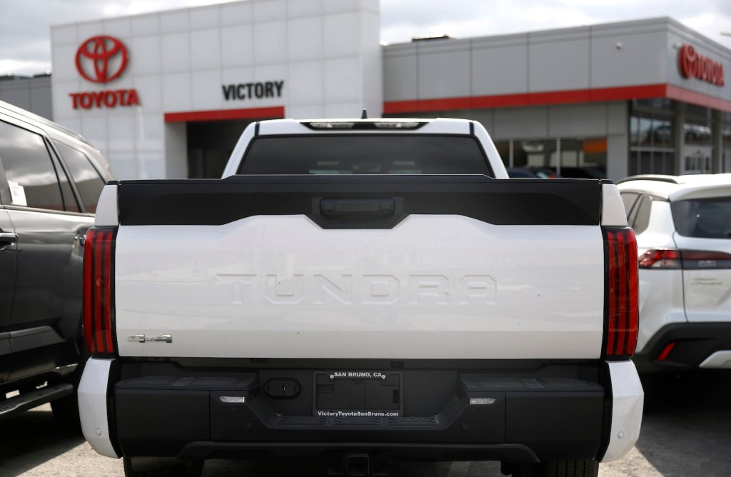 The tailgate of a white Toyota Tundra pickup truck parked outside a dealership.