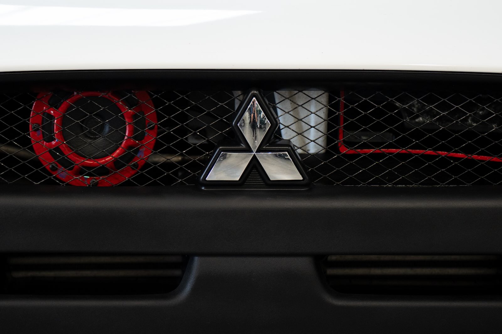 Mitsubishi three-point star logo on a grille at an auto show.