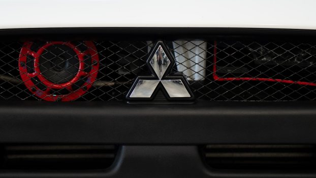 Mitsubishi three-point star logo on a grille at an auto show.