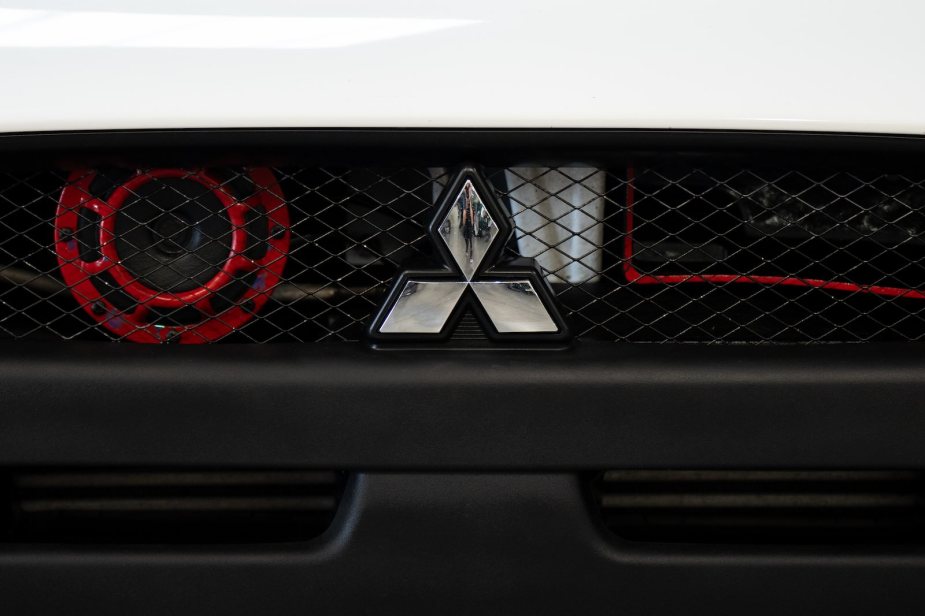 Mitsubishi three-point star logo on a grille at an auto show.