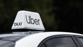 The Uber/Taxi sign on the roof of a white car.