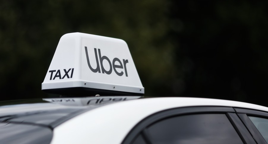 The Uber/Taxi sign on the roof of a white car.