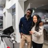 Used car buyers standing in a dealership consider an EV.