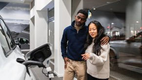 Used car buyers standing in a dealership consider an EV.