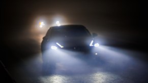 Two cars with bright headlights driving at night
