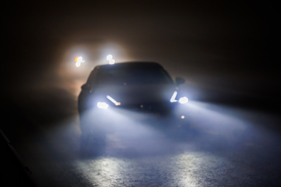 Two cars with bright headlights driving at night