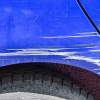 A blue car with a big paint scratch in very close view