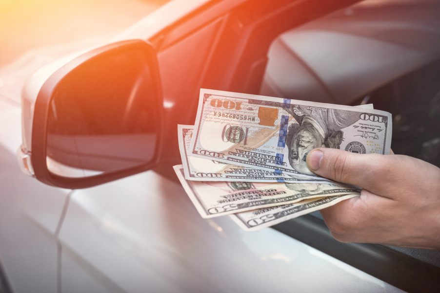 A driver holding cash in very close view of hand and side mirror