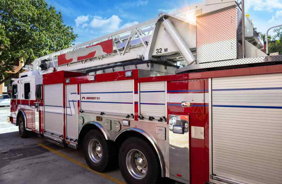 A fire department ladder truck parked in right rear angle view