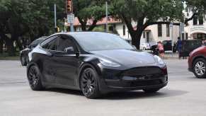 A black Tesla Model Y driving though an intersection in right front angle view