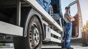 Tow truck driver stands with arms crossed in front of rig