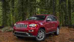 A red 2015 Jeep Grand Cherokee parked in the woods in left front angle view