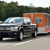 A black 2018 Ford F-150 towing a large "Built Ford Tough" branded box trailer