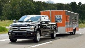 A black 2018 Ford F-150 towing a large "Built Ford Tough" branded box trailer