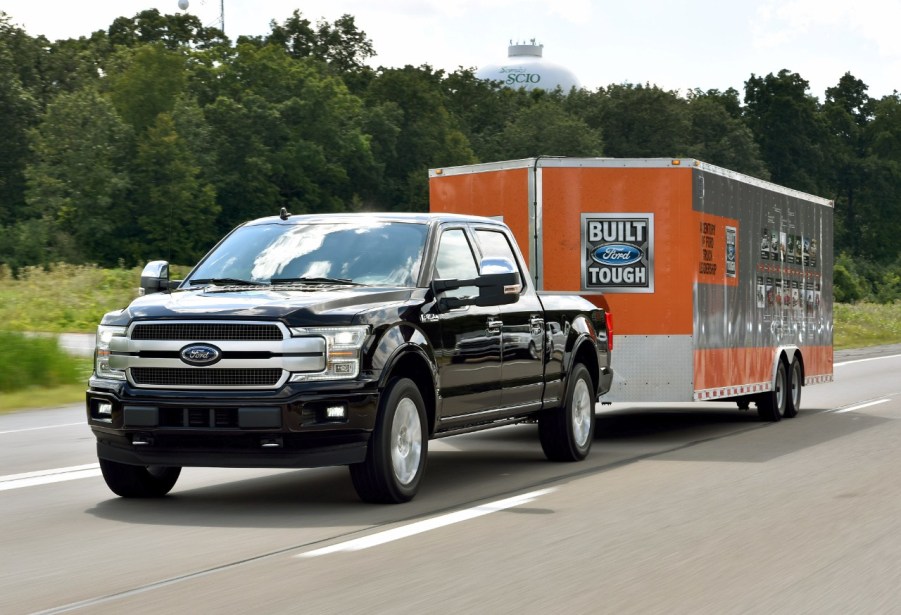 A black 2018 Ford F-150 towing a large "Built Ford Tough" branded box trailer