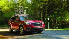 A red 2020 Subaru Forester with a bike roof rack driving uphill in right front angle view