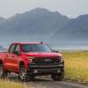 A red 2021 Chevrolet Silverado 1500 Trail Boss parked on a dirt road in right front angle view