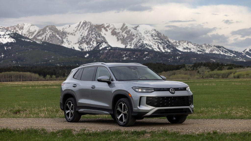 A silver 2025 Volkswagen Tiguan parked in front of snow-capped mountains in right front angle view