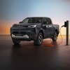 The 2026 Toyota Hilux EV pickup charging on a shadowy stage