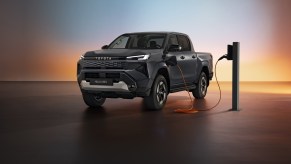The 2026 Toyota Hilux EV pickup charging on a shadowy stage