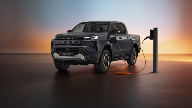 The 2026 Toyota Hilux EV pickup charging on a shadowy stage