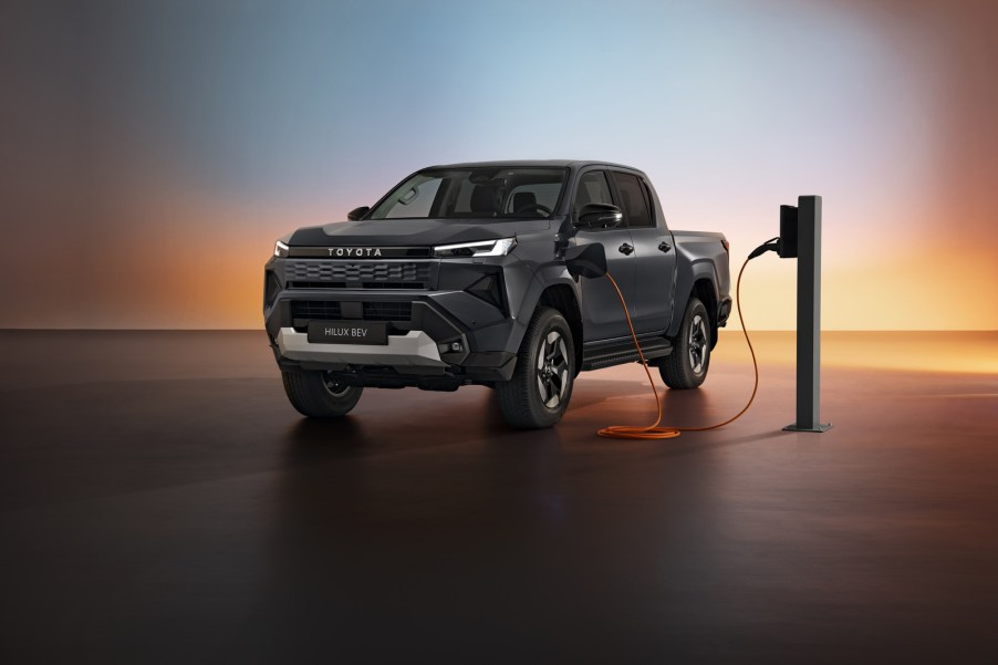The 2026 Toyota Hilux EV pickup charging on a shadowy stage