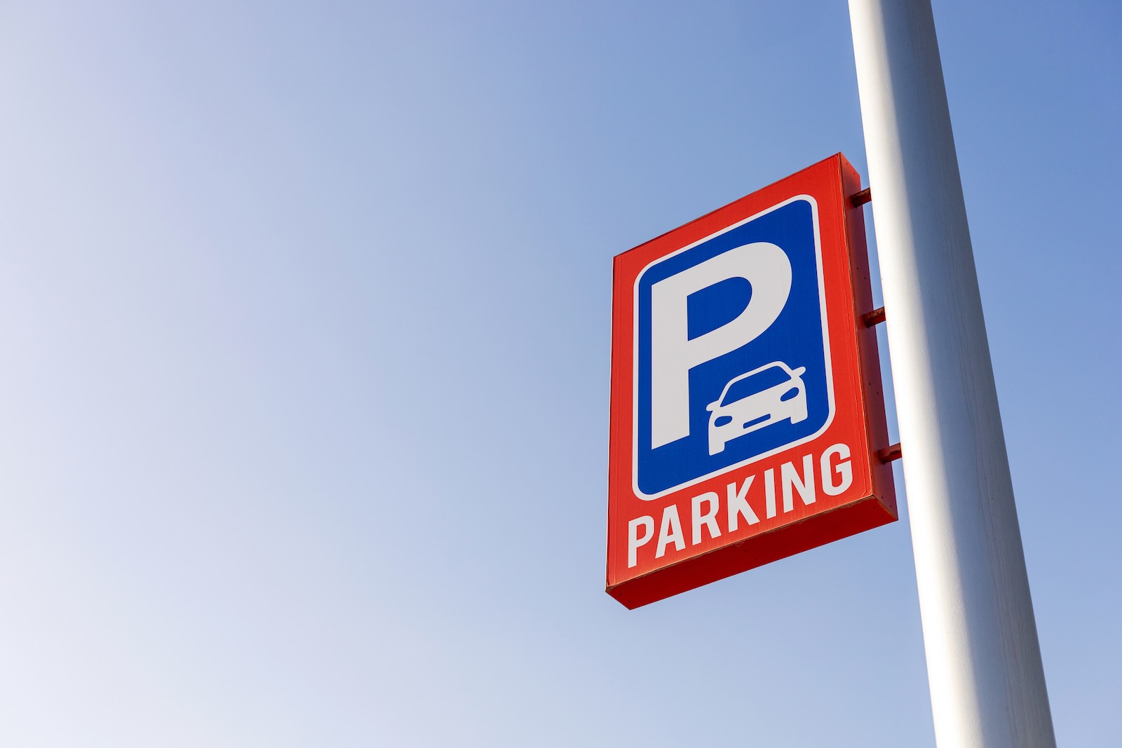 Parking sign on a pole above an airport lot.