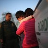 Child holds onto its mother outside a border patrol ICE agent's vehicle during a traffic stop