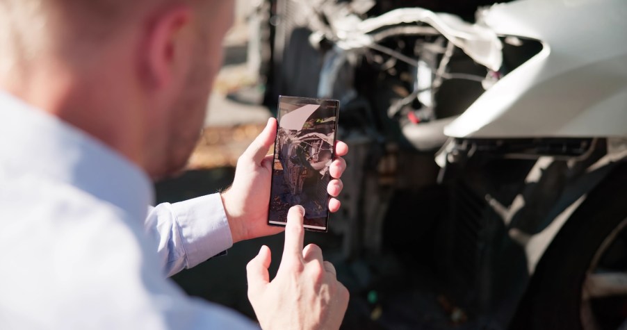 Insurance claims adjuster takes photos of a car crash.