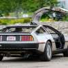 DeLorean sports car parked in a dirt lot with one gullwing door up