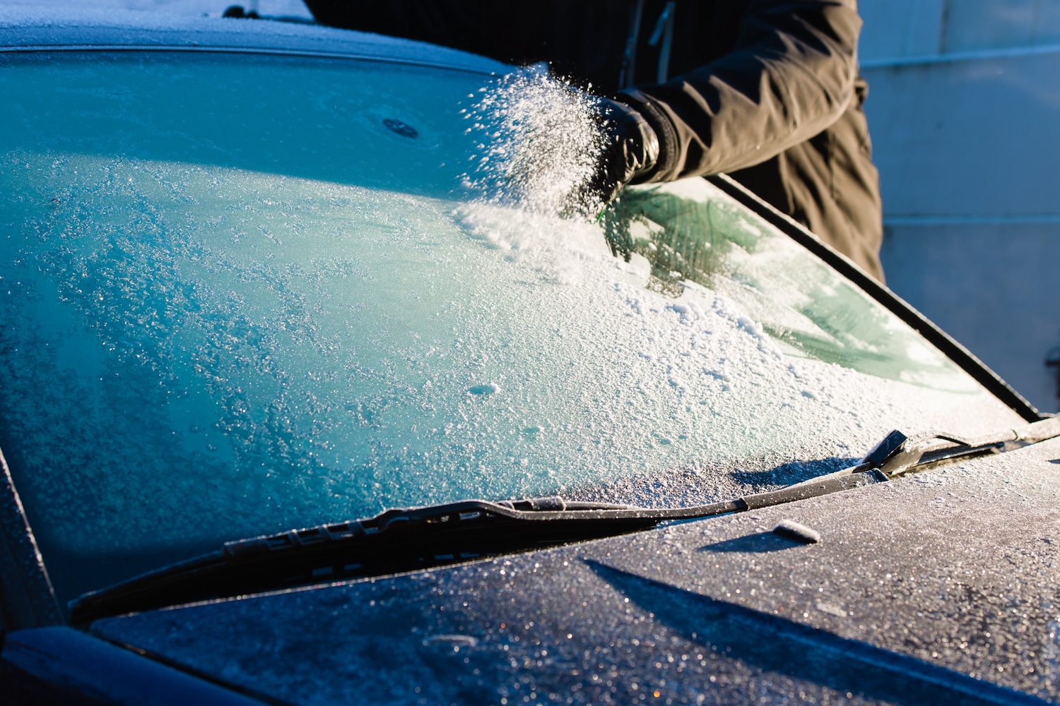 A man cleaning ice off windshield 