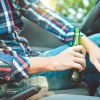 A man driving with an open beer