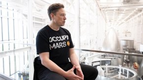 Elon Musk during a Space X interview sits in his factory wearing an Occupy Mars t-shirt