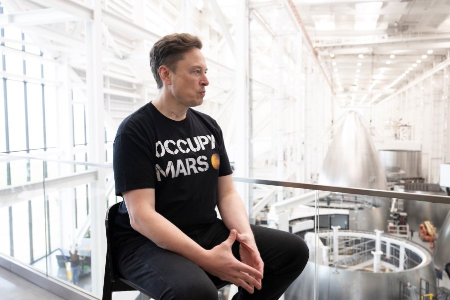 Elon Musk during a Space X interview sits in his factory wearing an Occupy Mars t-shirt